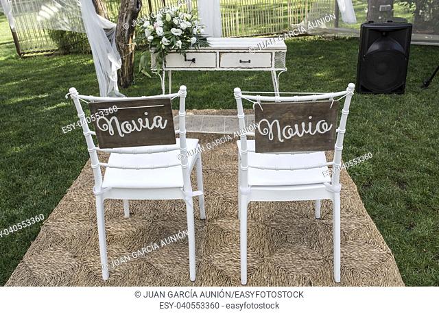 Chairs for bride and groom at altar. Spanish sign Novia y Novio