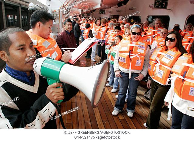 Lifeboat drill, passengers, lifejacket, Asian male crew. Holland America Line, MS Noordam. Manhattan. New York. USA
