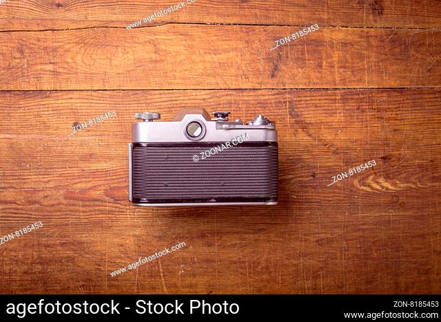 Retro camera on wood table background, vintage color tone