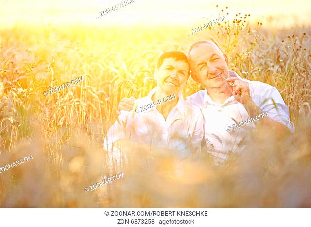 Zwei alte Bauern sitzen im Sommer zufrieden im Feld voller Weizen