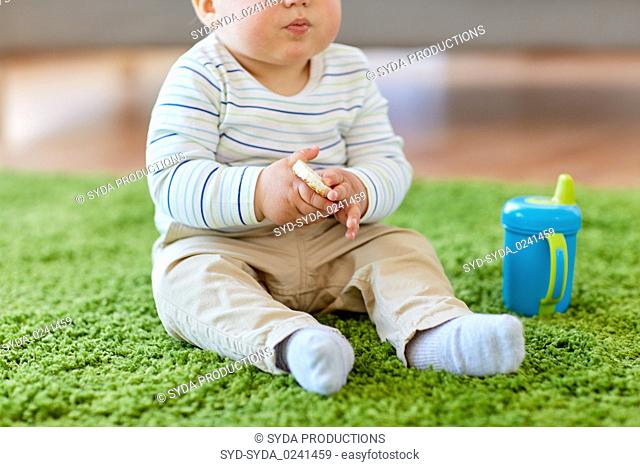 baby boy on floor and eating rice cracker at home