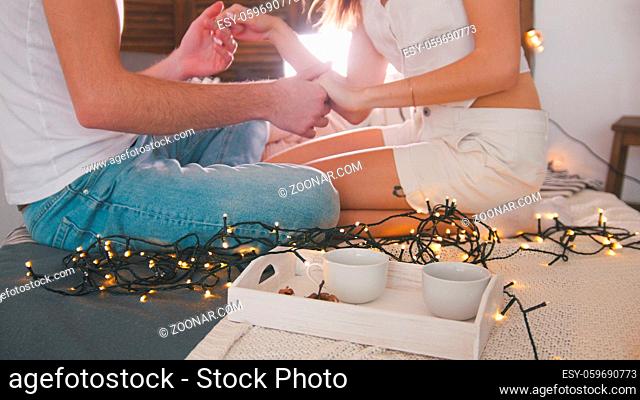 Young guy and girl sitting on the couch, laughing, talking and having fun with a lights, love and family relations