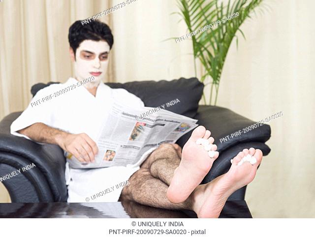 Man getting pedicure while reading a newspaper