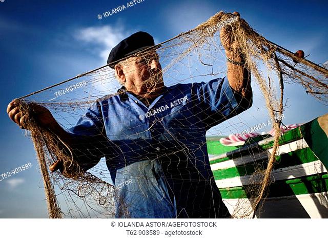 A fisherman prepares his nets out to fish  Costa Dorada, Tarragona, Spain