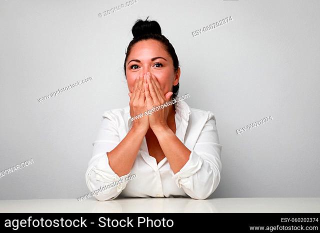 Image of young shocked woman smiling and covering her face. High quality photo