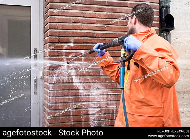 Man cleaning graffiti from wall
