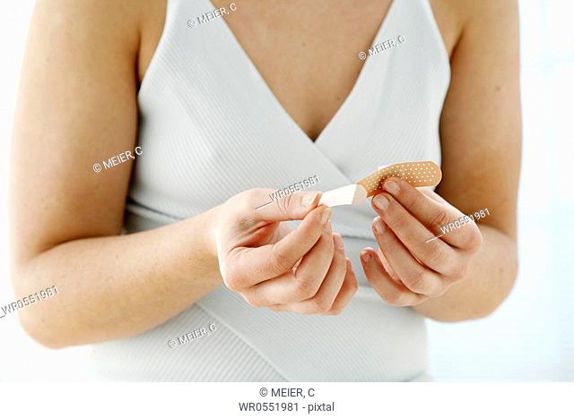 close up - young woman is opening a plaster - band-aid