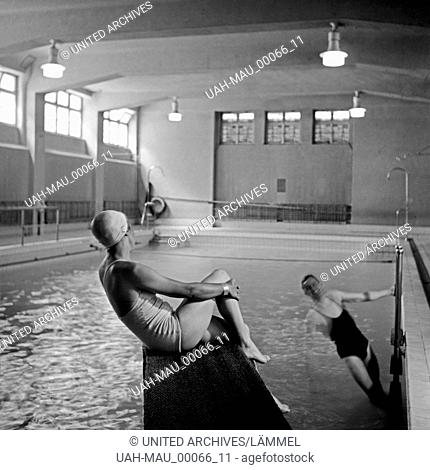 Eine junge Frau und ein junger Mann in einem Hallenbad, Deutschland 1930er Jahre. A young woman and a young man inside an indoor swimming pool, Germany 1930s