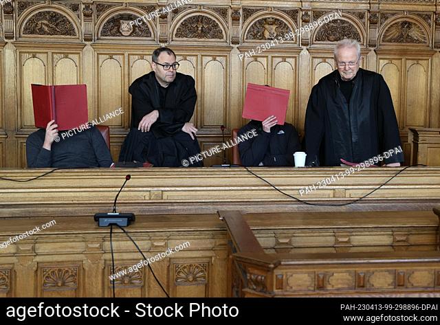 13 April 2023, Bremen: Two defendants wait with their defense lawyers in a hall of the Bremen Regional Court for their trial to begin