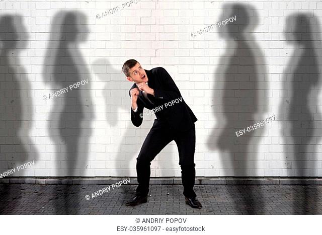 Young Businessman Getting Scared From The People Shadow Falling On Wall