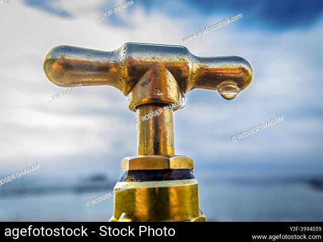 Water drops on a leaking brass tap handle