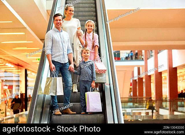 Glückliche Familie im Einkaufszentrum auf einer Rolltreppe mit vielen Einkaufstüten