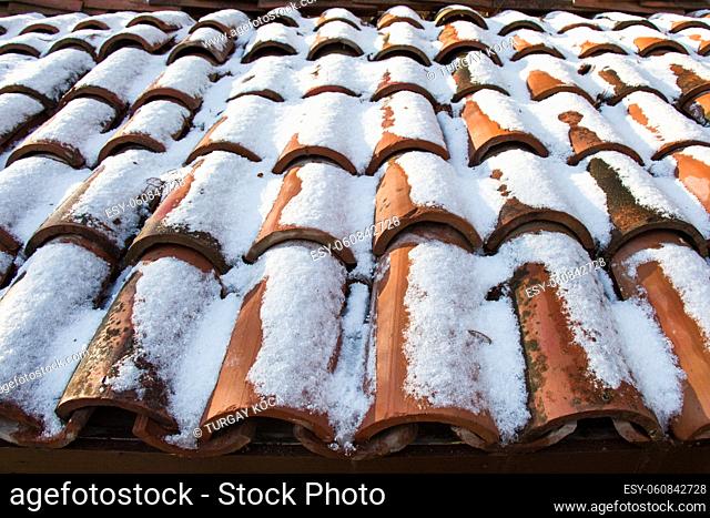 Brown tiles slightly covered with white snow