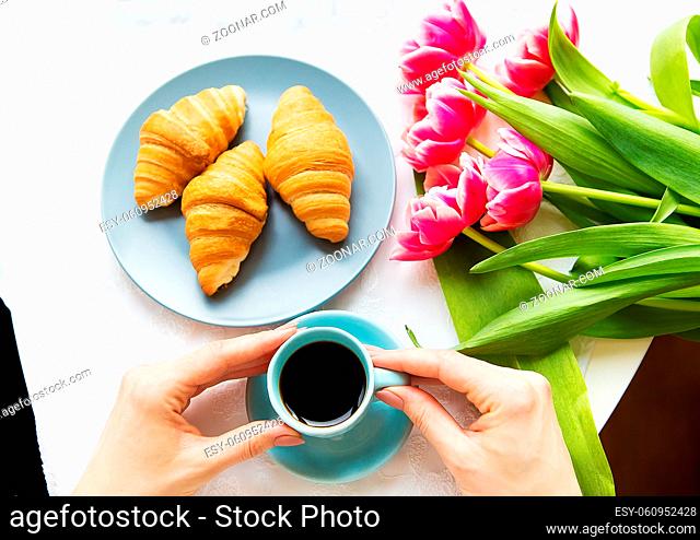 Girl with croissants and coffee, a bouquet of pink tulips, happy morning