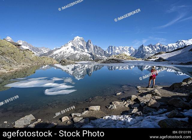 Young woman in front of mountain panorama, reflection in Lac Blanc, mountain peaks, Grandes Jorasses and Mont Blanc massif, Chamonix-Mont-Blanc, Haute-Savoie