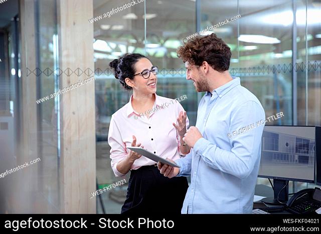 Smiling male and female entrepreneurs discussing at office