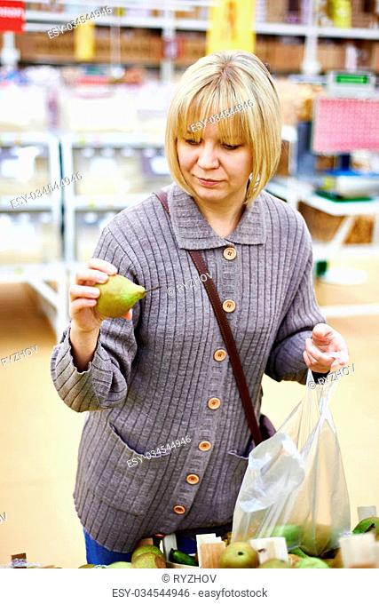 Young woman chooses pears in the store