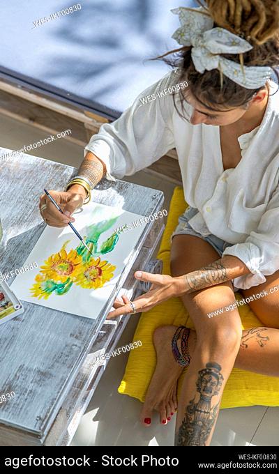 Artist painting sunflower on paper at home