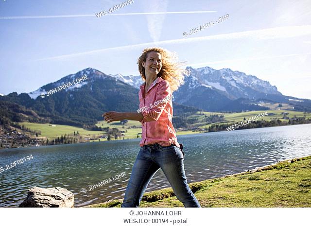 Austria, Tyrol, Walchsee, smiling woman walking at the lake