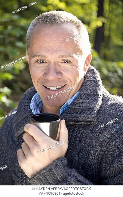 Older Man Walking in Woods Drinking from a Cup