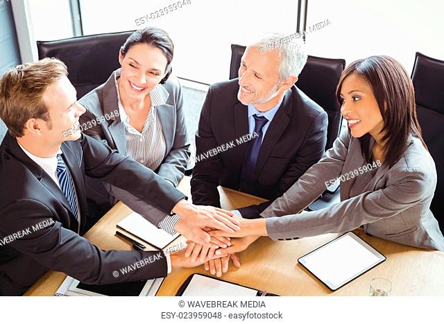 Businesspeople stacking hands in conference room
