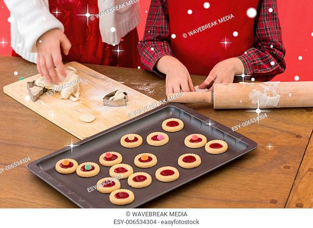 Composite image of festive little girls making christmas cookies