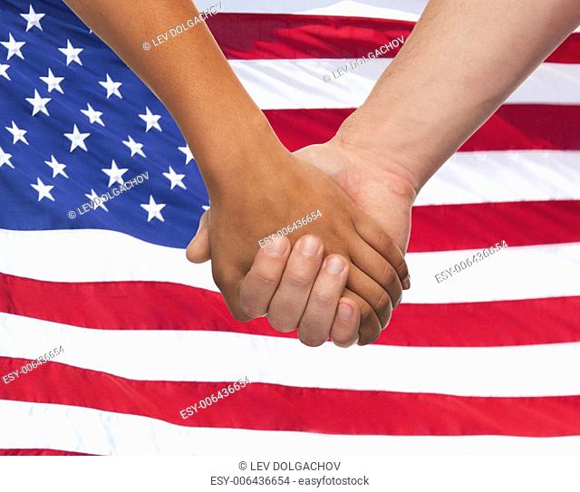 friendship, patriotism, gesture and people concept - closeup of two hands hands holding over american flag