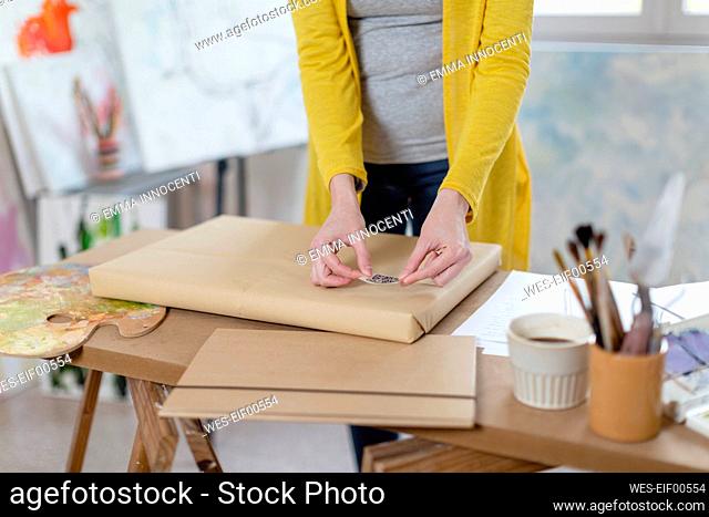 Woman sticking bar code on delivery package at home studio