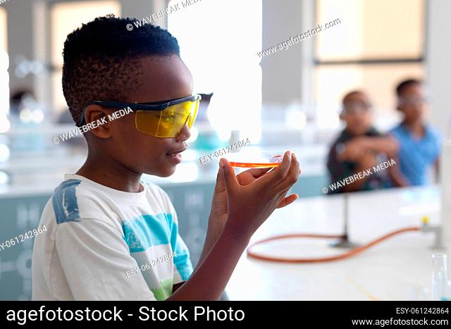 African american elementary schoolboy performing scientific experiment during chemistry class
