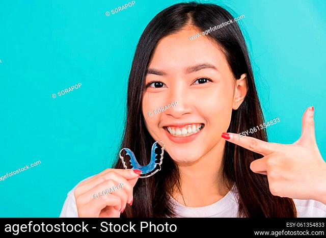Female hold teeth retaining tools after removable braces, Portrait young Asian beautiful woman smiling pointing with finger silicone orthodontic retainers for...