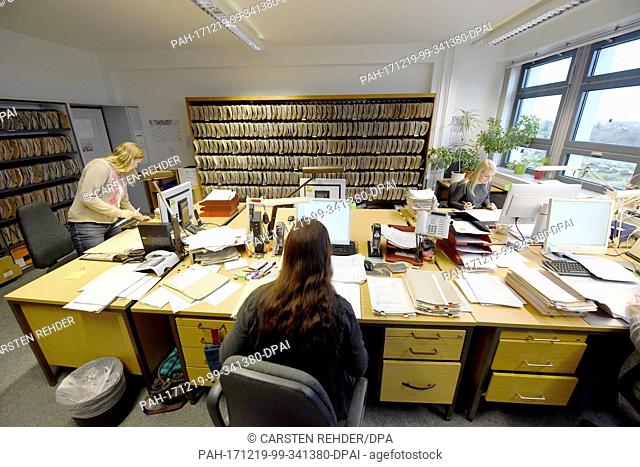 Employees work at desks with files at the Federal Office of Motor Vehicles ('Kraftfahrt-Bundesamt', KBA) in Flensubrg, Germany, 8 December 2017