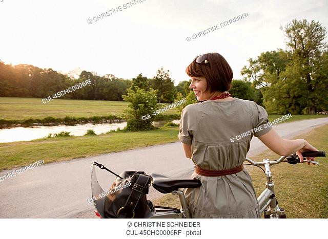 Woman walking bicycle on rural road