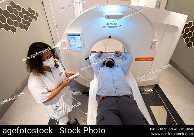 23 July 2021, Lower Saxony, Hanover: Neslian Ciftci, medical-technical radiology assistant, talks to study participant Martin Scheele in a mobile CT computer...