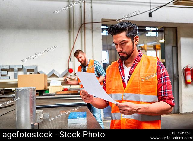 Facharbeiter als Lagerist und Kommissionierer liest einen Auftrag in der Werkstatt im Betrieb