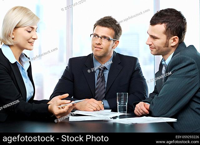 Businessmen listening to businesswoman explaining work at office meeting