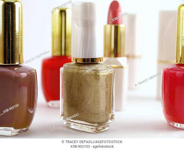 Make up grouping. Red, brown, fuschia, and gold nail polish in bottles. With lipstick tubes in the background. Horizontal, Silo. Isolated