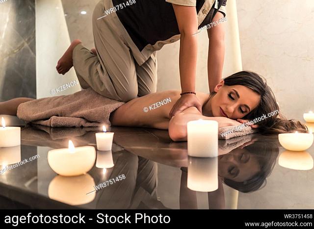 Young woman lying down while enjoying the acupressure techniques of traditional Thai massage at luxury spa and wellness center
