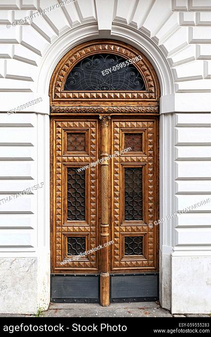 Details of European style classic old-fashion elegant wood carving door panels made of wood and decorated with wrought iron at a white concrete building in Rome