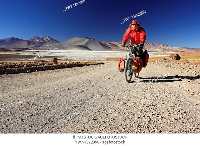 A man is cycling on the way from Paso de Sico to San Pedro de Atacama, Chile, Antofagasta region
