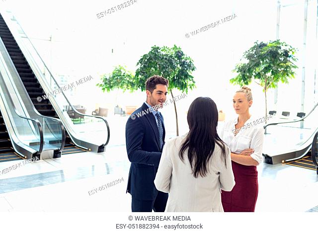 Diverse business people interacting with each other while standing in front of escalators