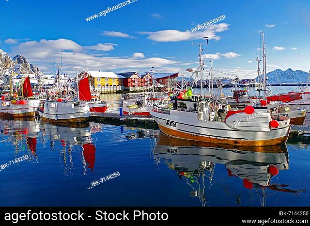 Fishing boats with red sails reflected in the water, buildings and hotels in the background, Austvågøya, Svolvaer, Scandinavia, Norway, Europe