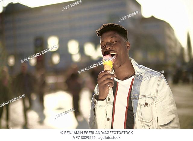 Young man eating ice cream cone, in Munich, Germany