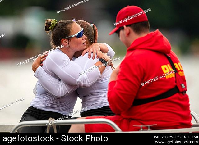 25 August 2023, North Rhine-Westphalia, Duisburg: Canoe: World Championship, Final, Canadier two-man, 200m. Lisa Jahn (l) and Hedi Kliemke embrace a lifeboat