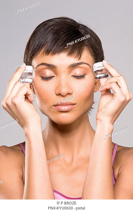 Woman rubbing ice cubes on her temples