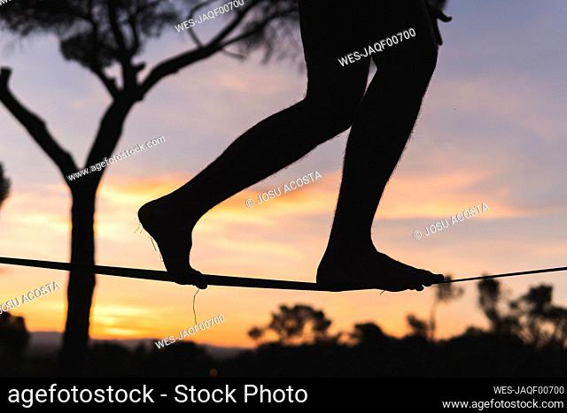 Man walking on tightrope during sunset