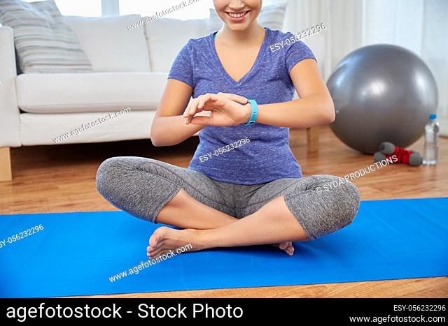 woman with fitness tracker doing yoga at home