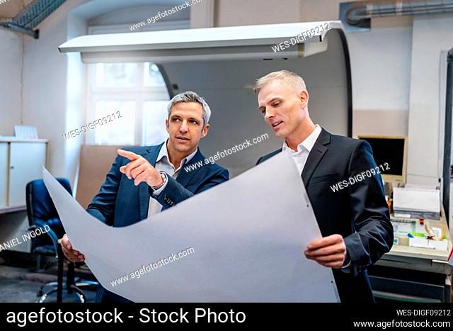 Two businessmen discussing a plan in a factory