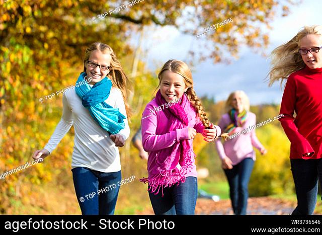 Girls running ahead at family walk through the park in fall or autumn