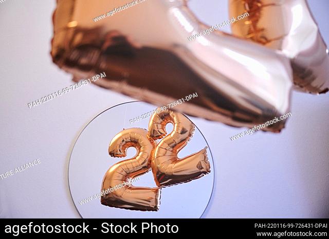 PRODUCTION - 13 January 2022, Berlin: ILLUSTRATION - Two golden balloons in the shape of the number 2 are reflected in a mirror