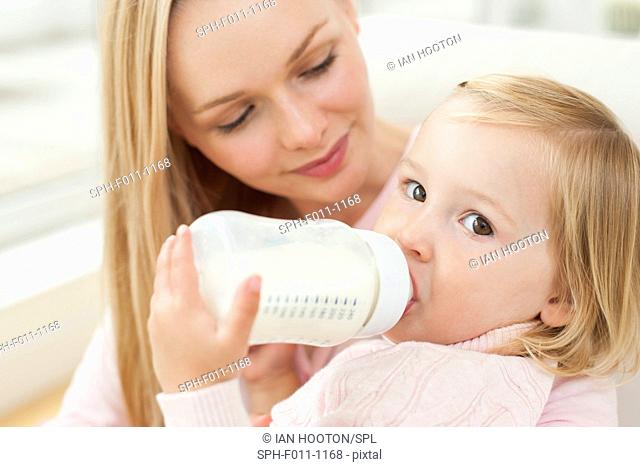 Mother with daughter drinking a bottle of milk